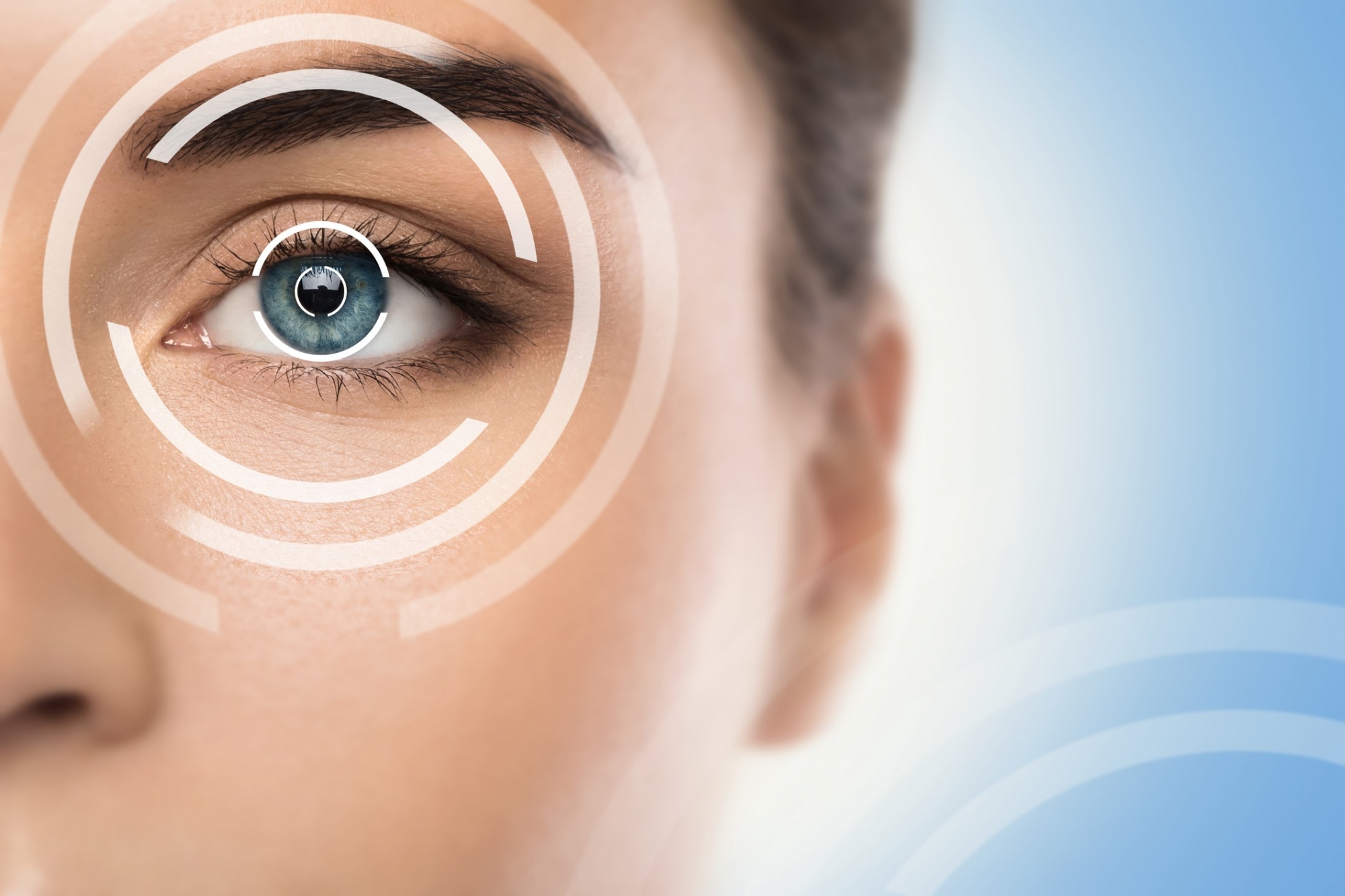Close-up of a woman's blue eye overlaid with concentric laser-targeting rings, representing LASIK vision correction.